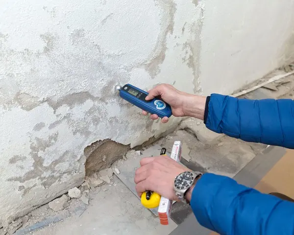 Feuchtemessung an einer Wand. Die isotec Kosten pro qm für eine Sanierung hängen vom Ausmaß des Schadens ab.