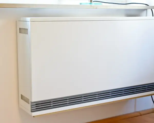 Ein weißes, modernes Heizgerät an der Wand, bereit, eine alte Nachtspeicherheizung zu ersetzen.