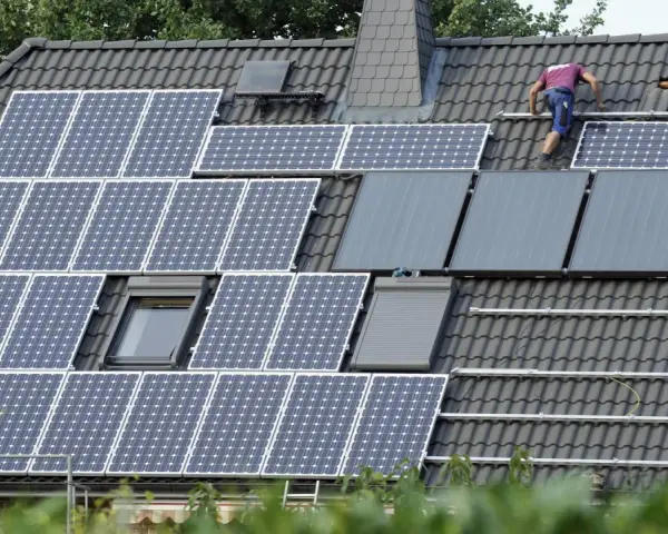 Arbeiter installieren eine PV-Anlage nach 20 Jahren auf einem Dach.