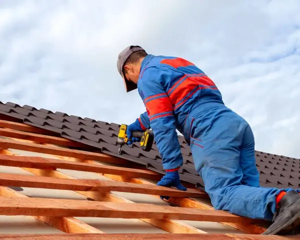Handwerker montiert mit Akkuschrauber neue Dachziegel. Informieren Sie sich über die **Blechdach Kosten** für Ihr Projekt.