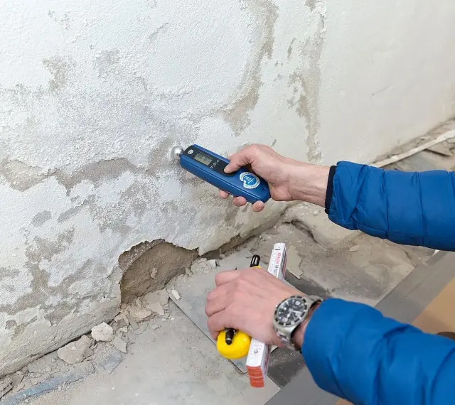 Feuchtemessung an einer Wand. Die isotec Kosten pro qm für eine Sanierung hängen vom Ausmaß des Schadens ab.