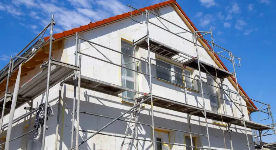 Haus mit Gerüst für Fassadensanierung. Die Kosten für eine Fassadensanierung können stark variieren.