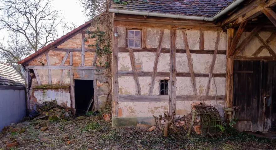 Ein altes Fachwerkhaus wartet auf seine Sanierung. Die Holzbalken und Lehmwände zeigen deutliche Spuren der Zeit.