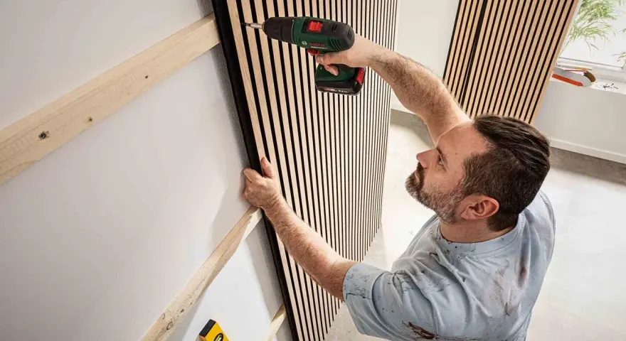 Mann montiert Akustikpaneele an Wand. Tolle Ideen für moderne Raumgestaltung und Schallschutz.
