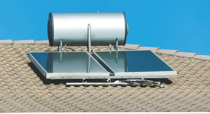 Ein pvt kollektor mit einem Warmwasserspeicher auf einem Ziegeldach unter blauem Himmel.