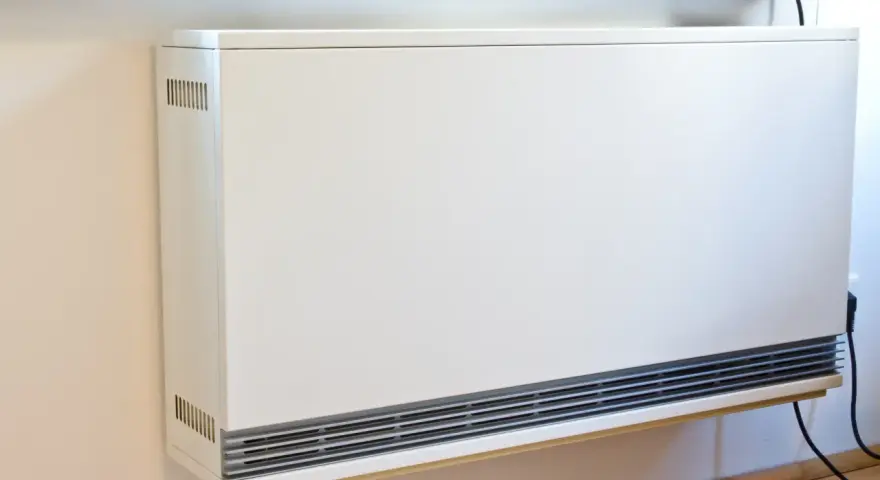 Ein weißes, modernes Heizgerät an der Wand, bereit, eine alte Nachtspeicherheizung zu ersetzen.