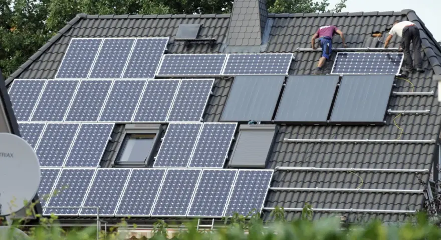Arbeiter installieren eine PV-Anlage nach 20 Jahren auf einem Dach.