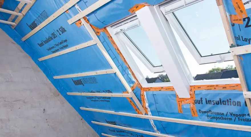 Konterlattung auf blauer Dampfbremse, die für die Dachisolierung vorbereitet wird. Dachfenster sind eingebaut.