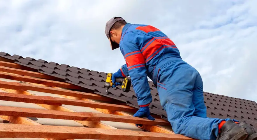 Handwerker montiert mit Akkuschrauber neue Dachziegel. Informieren Sie sich über die **Blechdach Kosten** für Ihr Projekt.