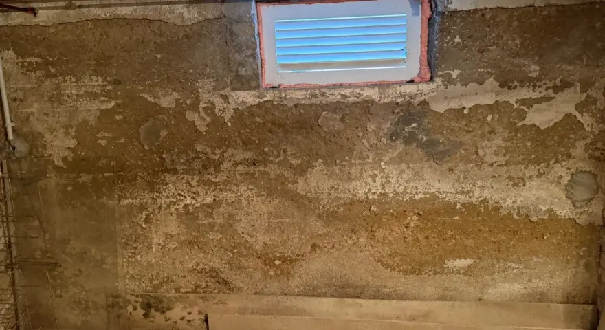 Feuchte Wände im Keller eines alten Hauses, deutet auf Grundwasser im Keller hin. Ein kleines Fenster ist sichtbar.