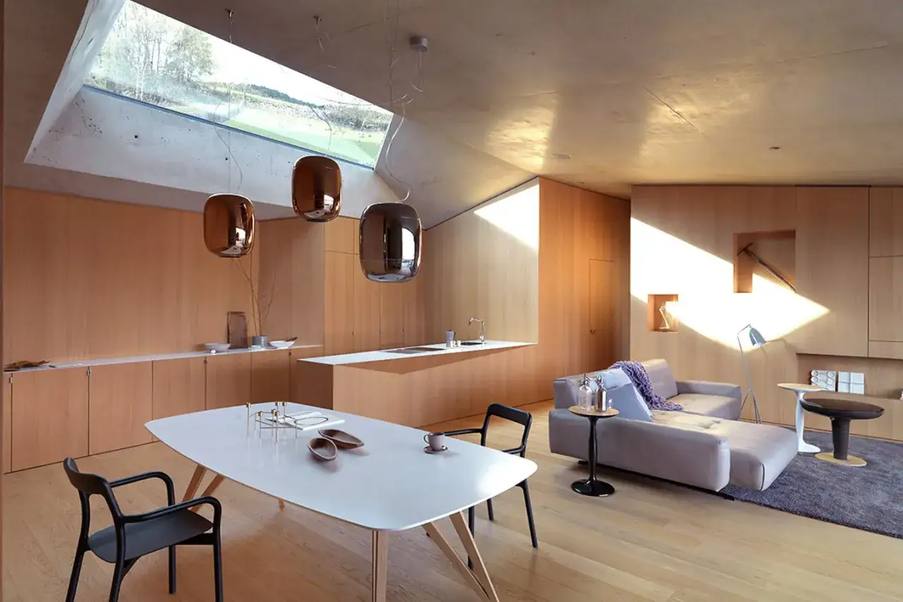 Modernes Wohnzimmer mit Essbereich, viel Holz und einem Dachfenster. Verschiedene Hartholzarten schaffen eine warme Atmosphäre.