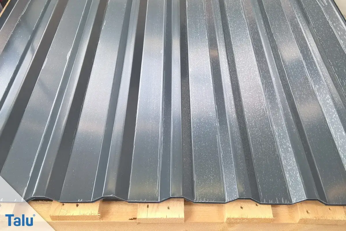 Graue Trapezblechplatten auf Holzpaletten. Informieren Sie sich über die Blechdach Kosten für Ihr Bauprojekt.