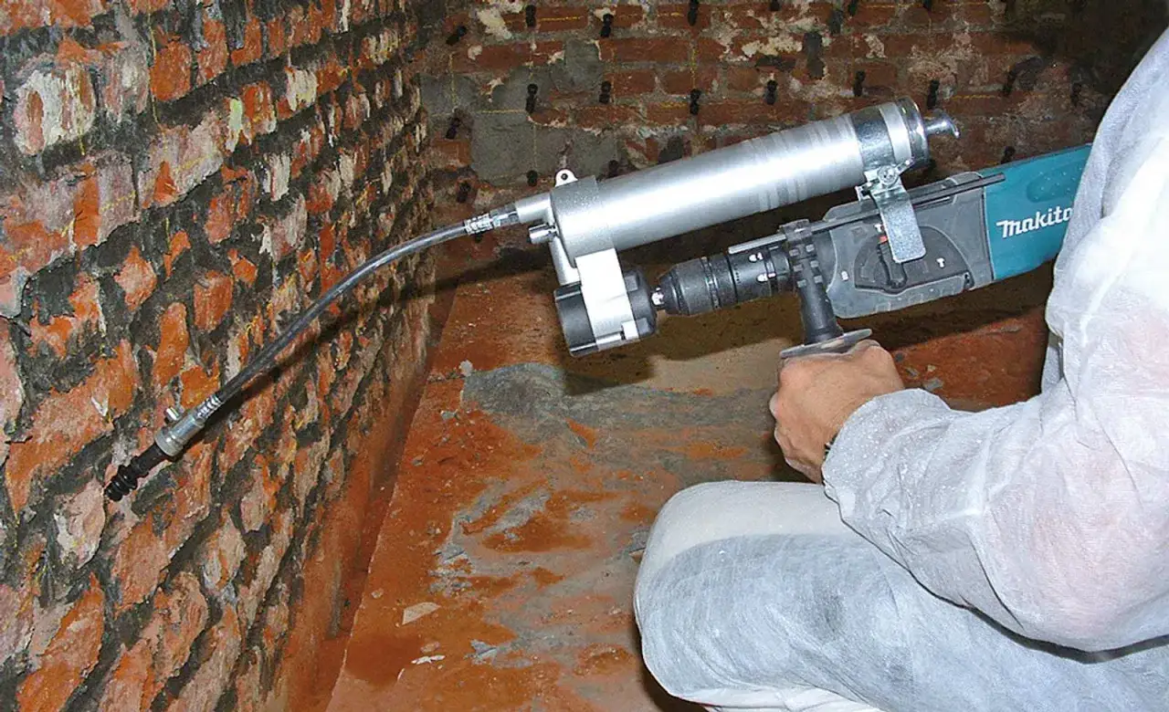 Hand bohrt L&ouml;cher in eine Ziegelwand, um eine Heizungsnische zumauern zu k&ouml;nnen.
