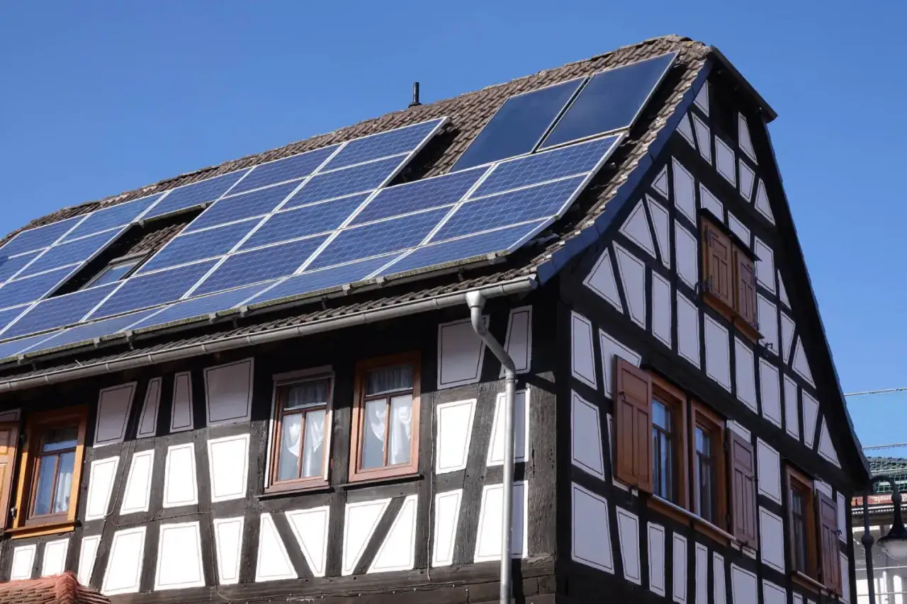 Fachwerkhaus sanieren: Solarpaneele auf dem Dach eines traditionellen Hauses mit sichtbaren Holzbalken und weißen Gefachen.