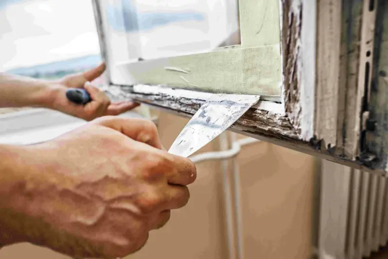 Hände entfernen mit Spachtel alten Fensterkitt. Vorbereitung für das Fensterkitt erneuern.