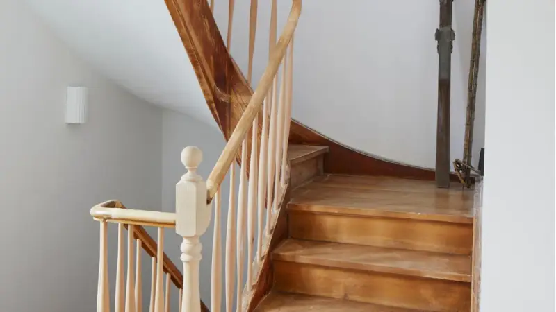 Eine alte Holztreppe wartet auf ihre Renovierung. Die Stufen und das Geländer aus hellem Holz zeigen Gebrauchsspuren, bereit für ein neues Leben.